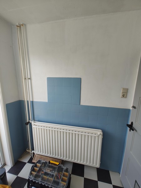 De radiator, de deur naar het droogplat, en de deur naar de overloop.